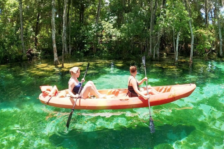 a group ofKayaking with Paddles Outdoor Rentals on a guided ecotour of Three Sisters Springs in Crystal River, Florida. people on a boat in the water